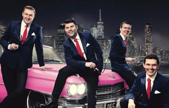 Oh What a Night singers sitting on a bright pink cadillac.