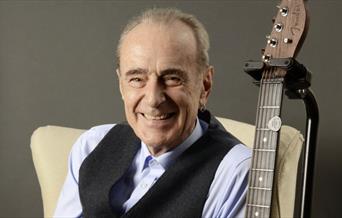 Francis Rossi sitting next to a guitar.