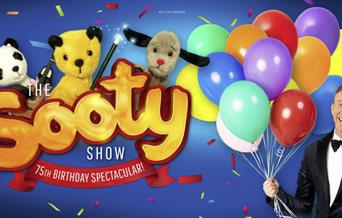 Sooty and friends on the left and Richard on the left holding balloons.