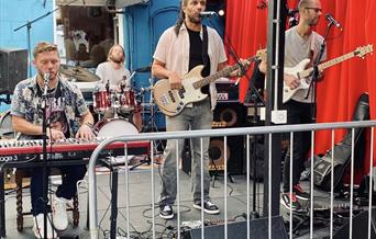 A band of four men  performing behind a fence