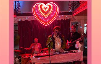 Image of The Elton John Experience playing a piano in front of a live audience.