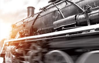 A blurred black, white and sepia image of the front of a steam train travelling at speed