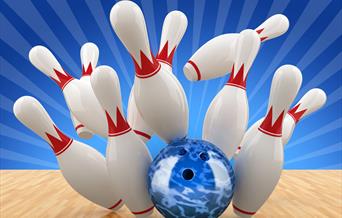 A blue bowling ball sending the pins flying at the end of a wooden bowling alley
