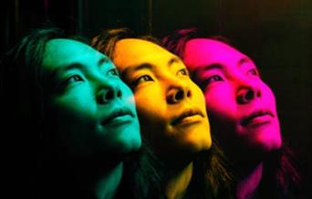 Theo Mizu in profile green, yellow and pink face on a black background