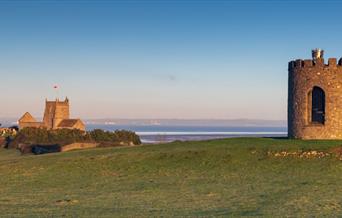 A beacon and a church separated by a green field