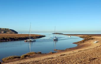 Uphill Beach and estuary near Weston-super-Mare. The image shows the sandy beach, boats in the estuary and a small island at the mouth of the estuary