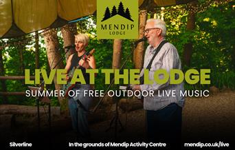 Two musicians (man and woman) playing guitar and singing into microphone under tented woodland canopy. Woodland trees in background. Mendip Lodge logo