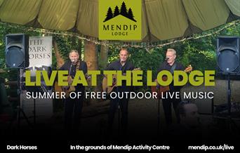 Three men playing guitar and singing into microphones under tented woodland canopy. Mendip Lodge logo. Text promotes Live at the Lodge: Summer of free