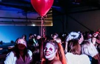 People in Halloween costumes partying and holding a red balloon