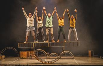 A group of fiver circus performers standing on a platform