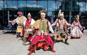 A group of five dancers in Cossack-style costumes
