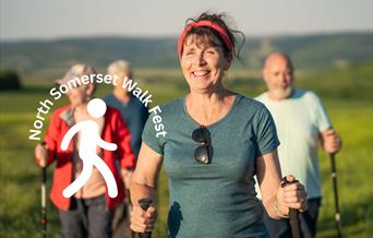 A group of four walkers with walking poles out on a ramble through countryside on a sunny day