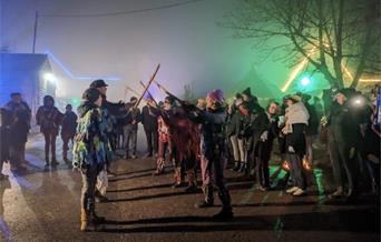 Image of a wassail festival with people creating an arch from sticks