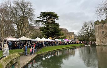 Christmas market stalls line the pretty banks of the river that forms a moat around the Bishop's Palace in Wells