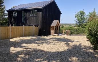 Outside view of a black wooden house and a shingle drive