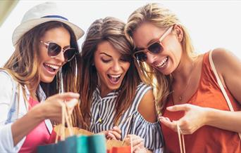 Three women looking excitedly at their shopping bags