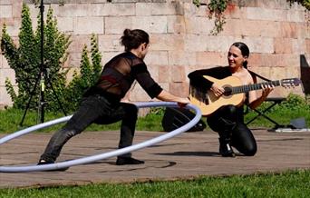Lady playing guitar, man inside large hoop