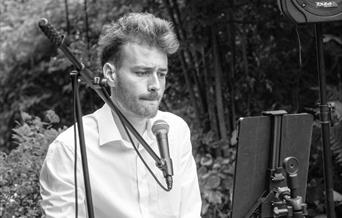 black and white picture of the artist at a keyboard in woodlands