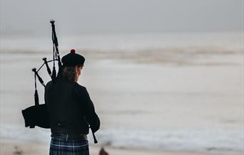 A bagpiper on the beach