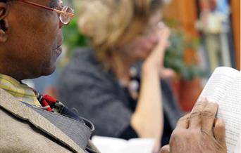 A man reading a book with a blurry background of another person reading a book.