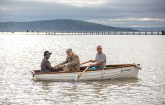 Three men in a row boat on a lake.