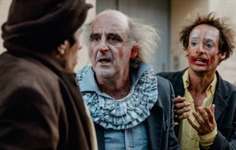 2 clowns looking at another, one is pleading