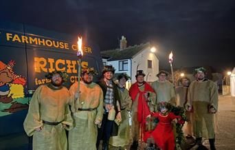 People in wassail costume in front of a van