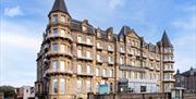 Exterior of a big four-storey hotel with turrets on the corners