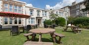 The lawns in front of the hotel with wooden bar tables