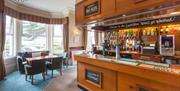 The bar with a table under a window overlooking gardens