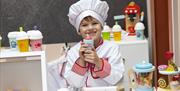 A child dressed as a chef in a make believe children's kitchen