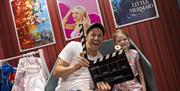 TV celebrity Joe Swash in a dressing room with a clapper board and a child sitting next to him