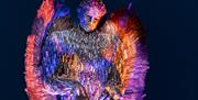 A statue in the shape of an angel which has been created out of confiscated knives and is floodlit in multi-colours