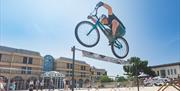Mountain Bike Stunt Rider Rich Pearson jumps over a high bar challenge in the Italian Gardens Weston-super-Mare