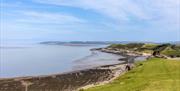 A grassy hill overlooking the sea and a rocky beach