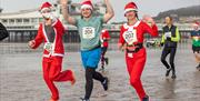 Runners in Christmas fancy dress wave to the camera as they compete in the Weston-super-Mare 10K Christmas Cracker run