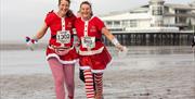 Two ladies in Santa Claus outfits during the Christmas Cracker 10K run on Weston-super-Mare Beach