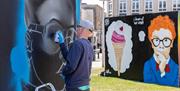 A spray can street artist filling in the detail of an eye on a piece of art in Weston-super-Mare