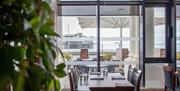 Interior shot of a restaurant looking past a dining table, out through a window with a view of a seaside pier