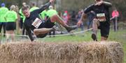 A competitor hurdles a hay bale