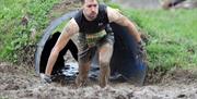 A competitor crawls out of a tunnel in an action race