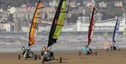 Four land yachts racing across a beach