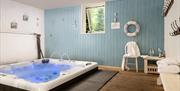 A large luxury hot tub jacuzzi bathroom with a blue wooden panelled feature wall at Webbington Farm Cottages near Weston-super-Mare