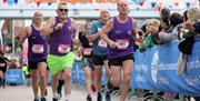 A group of runners being cheered by the crowd