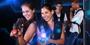 Two girls firing laser guns with two males in the background