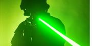 Silhouette of a person in a helmet firing a laser gun