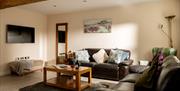 A luxury lounge in a farmhouse cottage at Webbington Holiday Cottages, Weston-super-Mare featuring two leather sofas and a wooden coffee table on a da