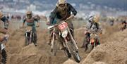 Motorbike riders battle on a sand made obstacle course during a beach race