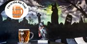 A pint of beer and a black cat set against a mural featuring a black cat and over-stamped with an I'm in the ale trail logo