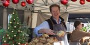 A stallholder serving up a savoury delight at the Eat:Weston food festival on his stall which is decorated with Christmas baubles and a Christmas tree